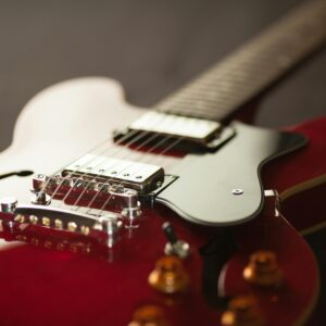 Detailed close-up of a red electric guitar showcasing the bridge and strings.